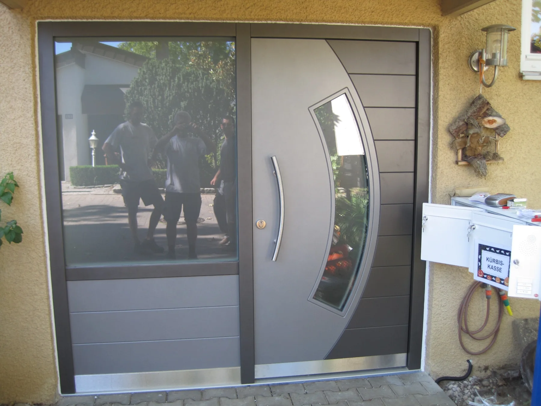 Individuelle Designhaustür in Grau Graue Designhaustür mit gebogenem Glasausschnitt und Seitenteil