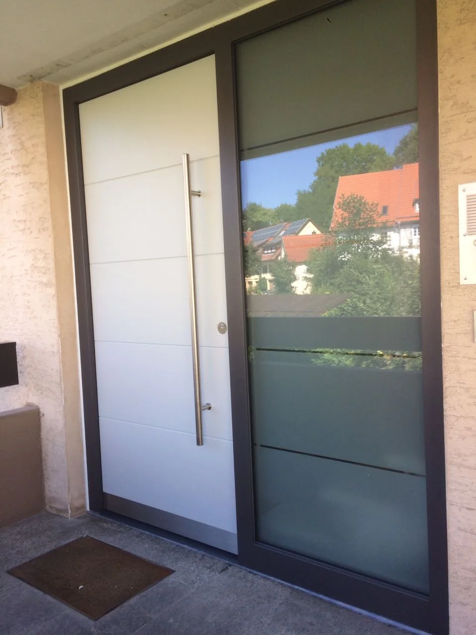 Moderne Haustür in Weiß Moderne weiße Haustür mit langem Edelstahlgriff und verglastem Seitenteil
